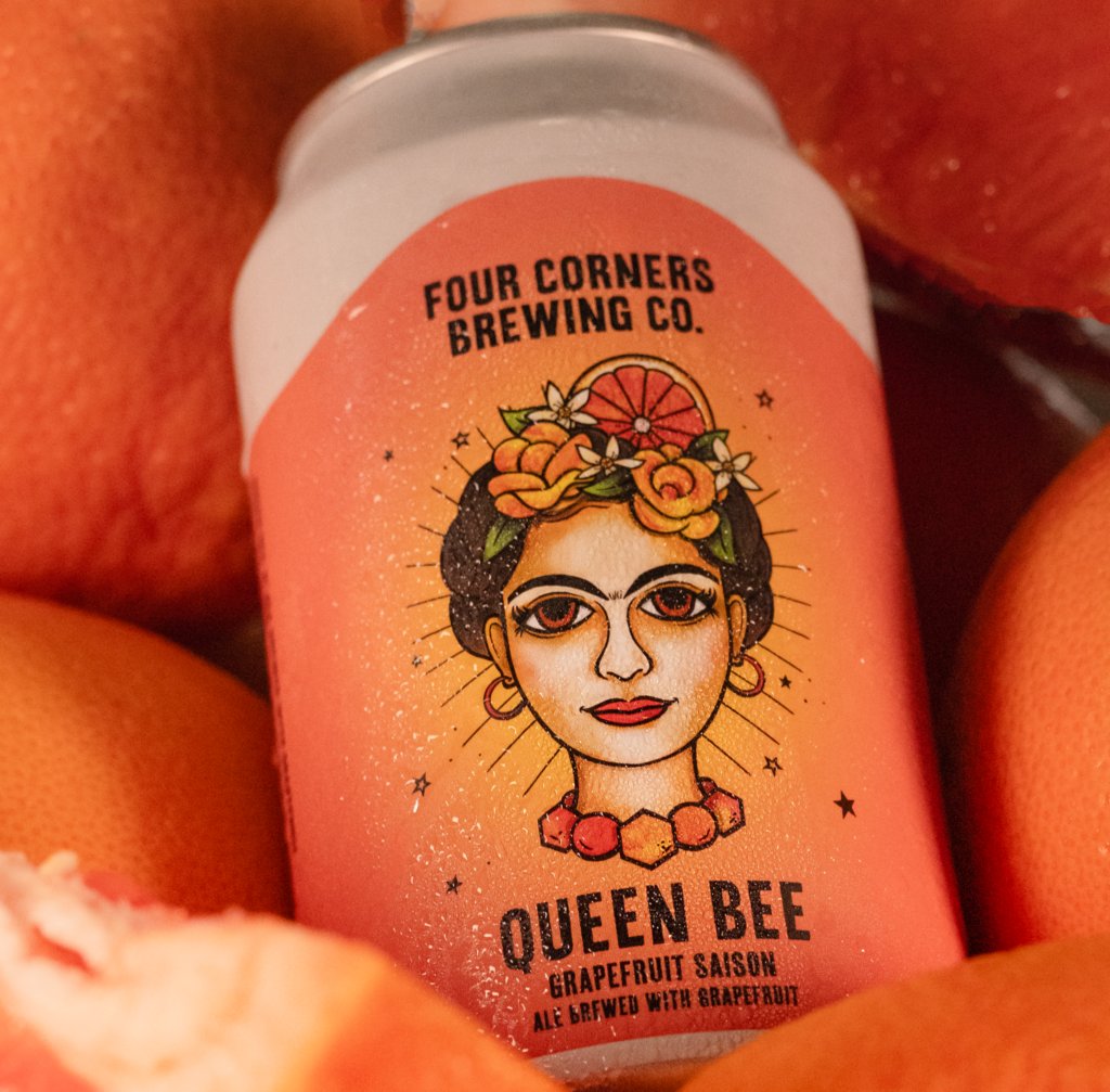 Can of Queen Bee Grapefruit Saison nestled among whole and sliced grapefruits, emphasizing its fresh Texas citrus ingredients.