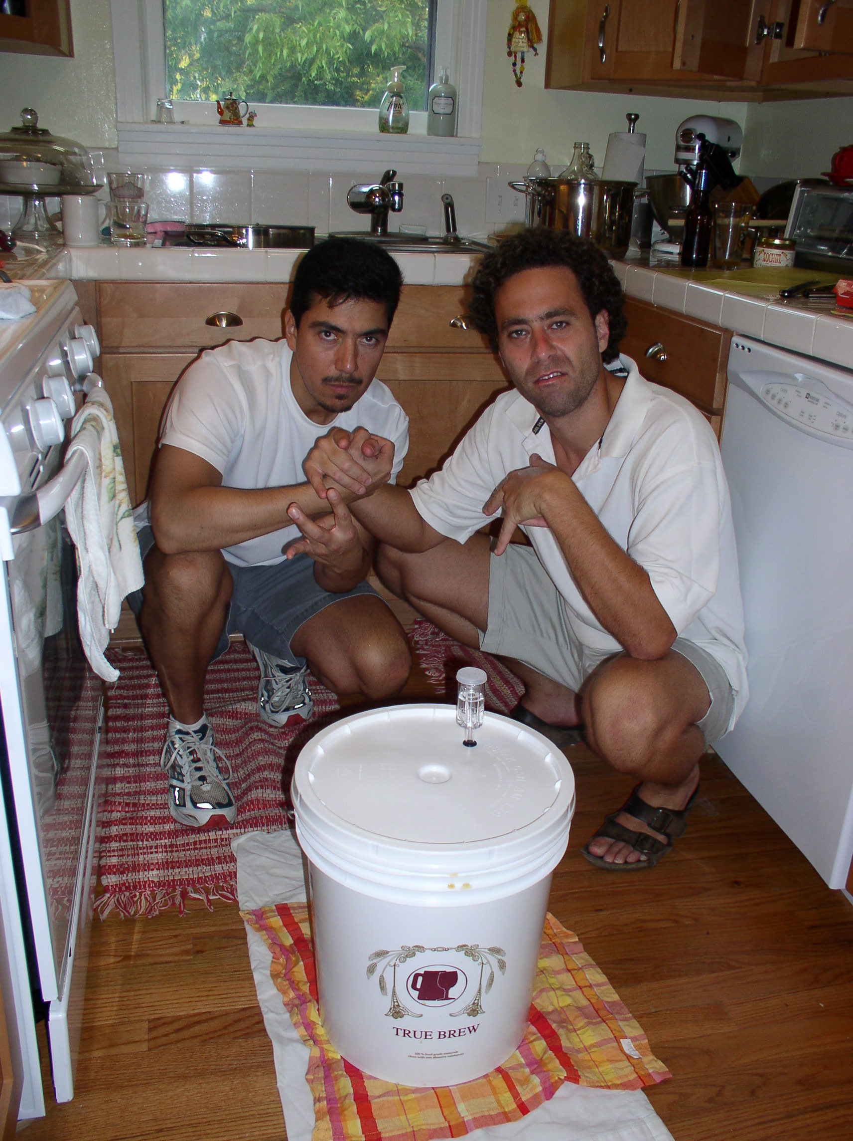 Two of Four Corners Brewing Co.'s founders crouched in a home kitchen, clasping hands over their first 5-gallon homebrew bucket
