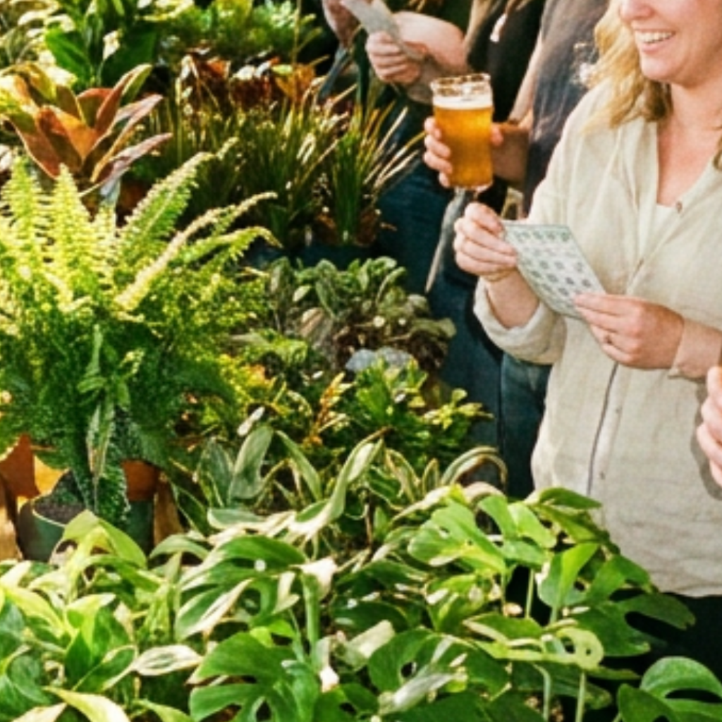 Smiling guest holding a pint of beer and a bingo card surrounded by lush tropical plants at a Four Corners plant event
