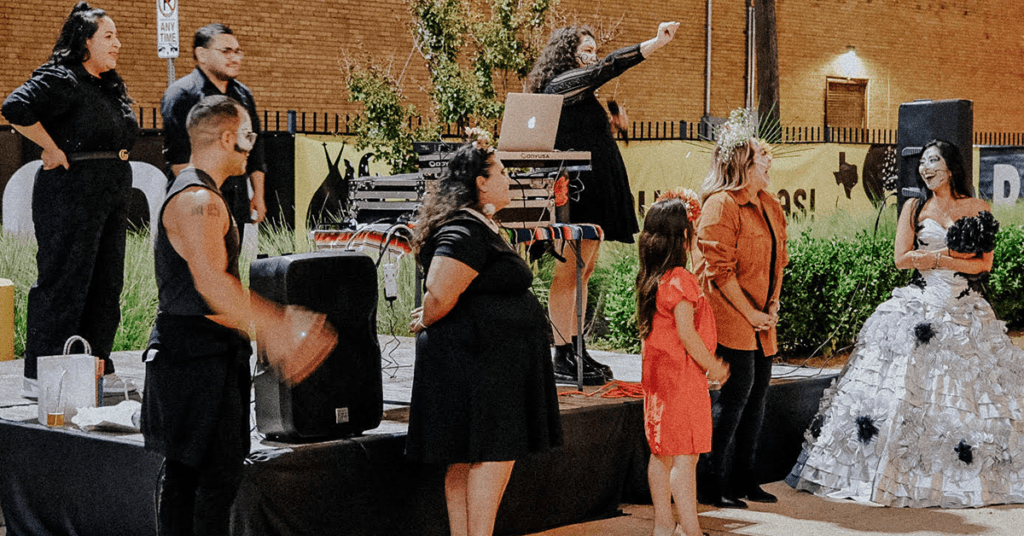 Performers and guests on an outdoor stage at Four Corners Brewing Co. Día de los Muertos celebration with DJ and decorative dress
